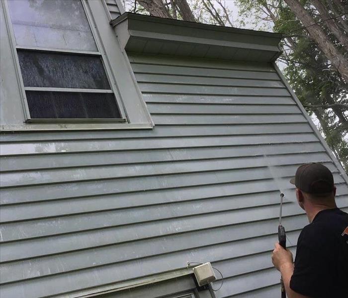 Crew Member pressure washing house